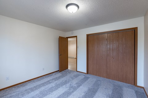 a bedroom of an empty apartment with a door to the hallway. Fargo, ND Briar Pointe Apartments