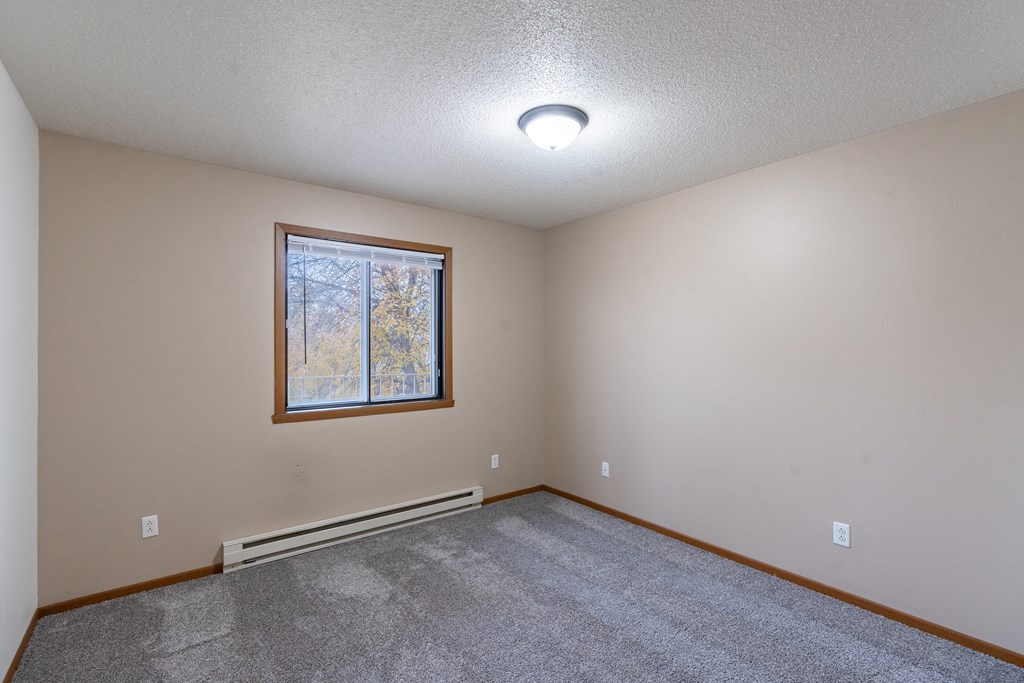 a bedroom with carpet and a window.Fargo, ND Briar Pointe Apartments