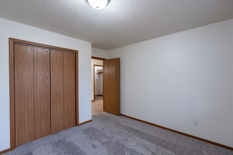 a bedroom with a closet and a door to a hallway. Fargo, ND Briar Pointe Apartments
