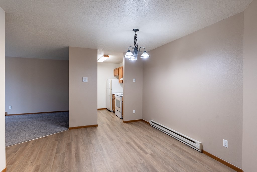 the living room and kitchen of an empty apartment with wood flooring. Fargo, ND Briar Pointe Apartments