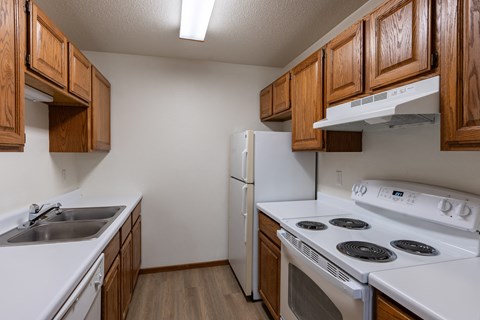 an empty kitchen with white appliances and wooden cabinets. Fargo, ND Briar Pointe Apartments