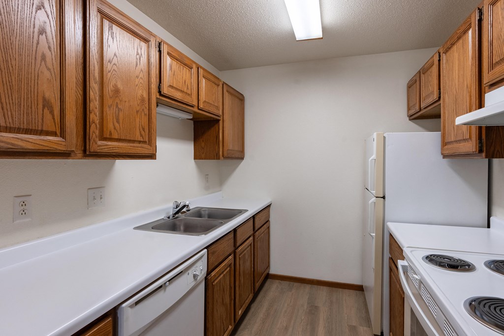 an empty kitchen with white appliances and wooden cabinets.Fargo, ND Briar Pointe Apartments