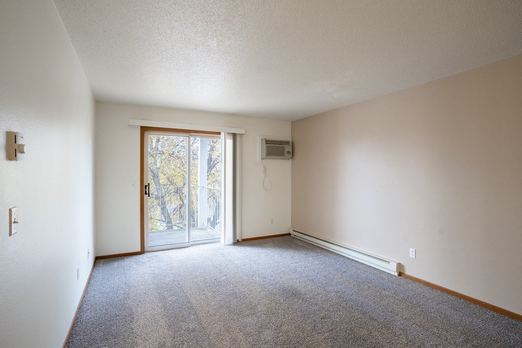 the living room of an apartment with carpet and a door to the patio. Fargo, ND Briar Pointe Apartments