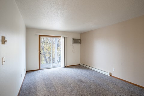 the living room of an apartment with carpet and a door to the patio. Fargo, ND Briar Pointe Apartments