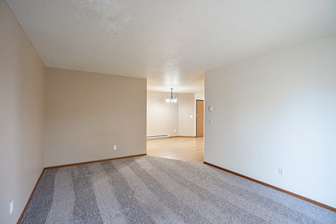 the living room and dining room of an apartment with carpeting and white walls. Fargo, ND Briar Pointe Apartments