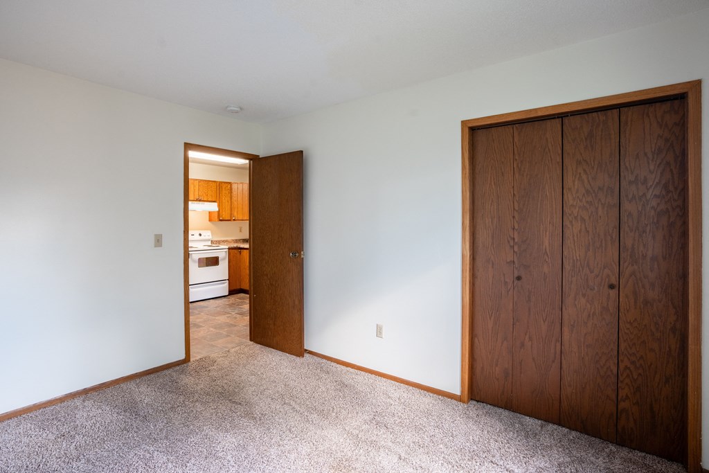 a bedroom with a closet and a door to a kitchen. Fargo, ND Brookfield Apartments