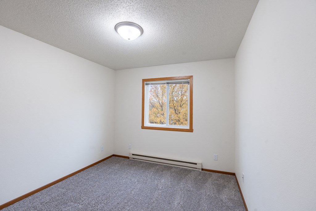 a bedroom with a window and carpet. Fargo, ND Brownstone Apartments
