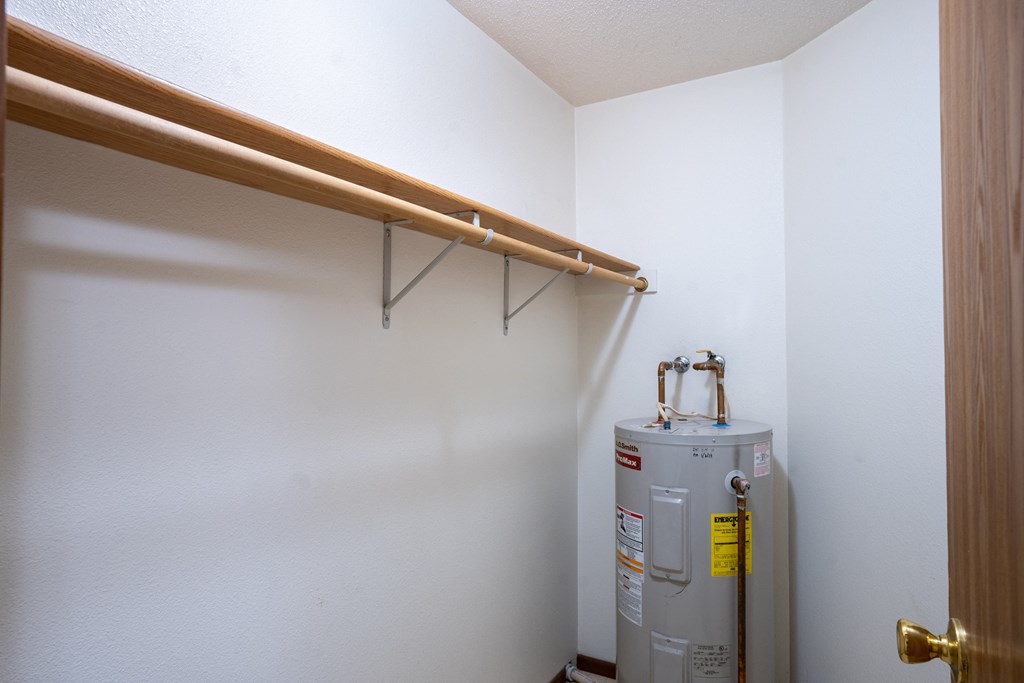 a room with a water heater and a pipe on the wall and a closet. Fargo, ND Brownstone Apartments