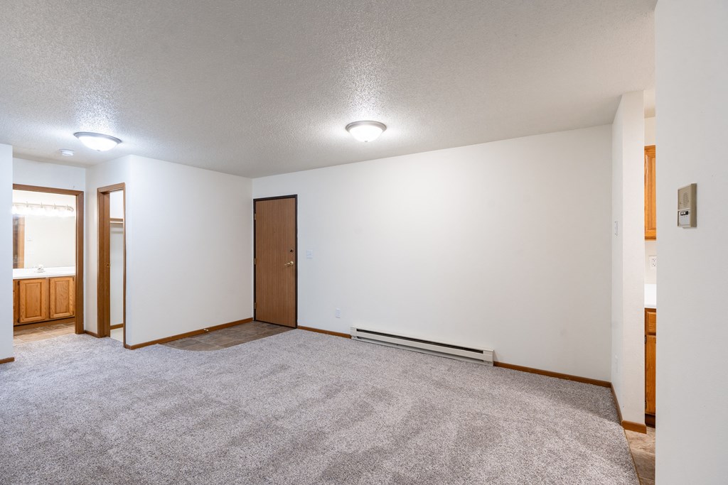 a dining room with a carpeted floor and a door to a bathroom. Fargo, ND Brownstone Apartments