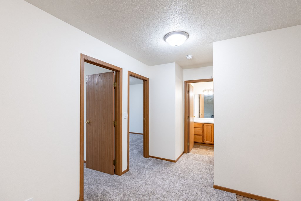 an empty room with two doors and a bathroom. Fargo, ND Brownstone Apartments