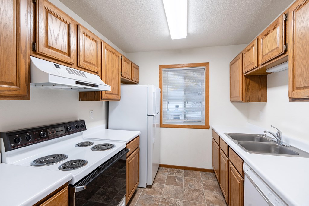 a kitchen with white appliances and wooden cabinets. Fargo, ND Brownstone Apartments
