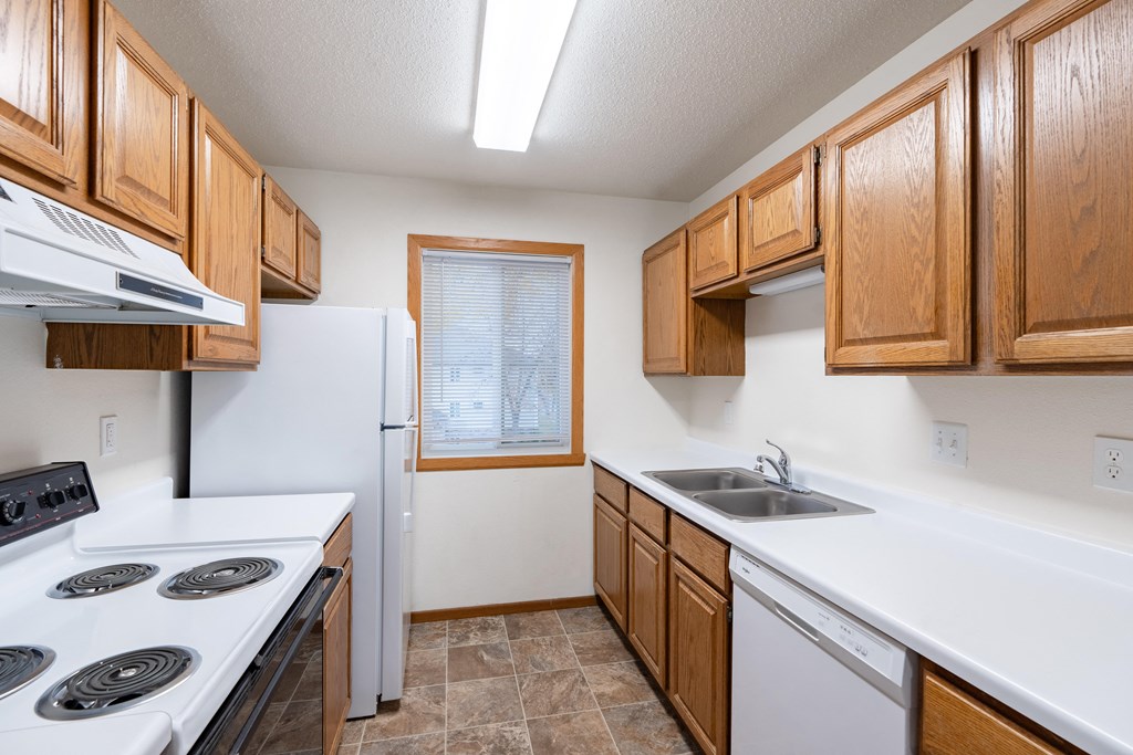 a kitchen with white appliances and wooden cabinets. Fargo, ND Brownstone Apartments