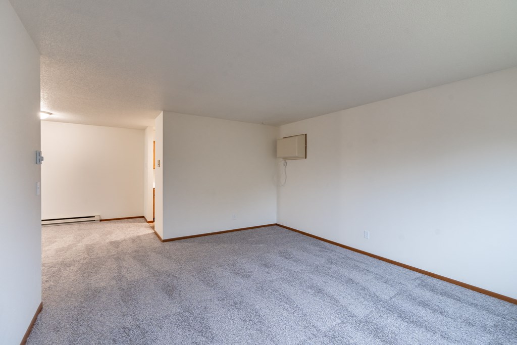 the living room and dining room of an apartment with carpet and white walls. Fargo, ND Brownstone Apartments