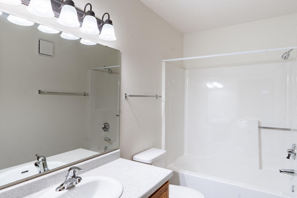a bathroom with a mirror and a sink and a shower. Fargo, ND Brownstone Apartments
