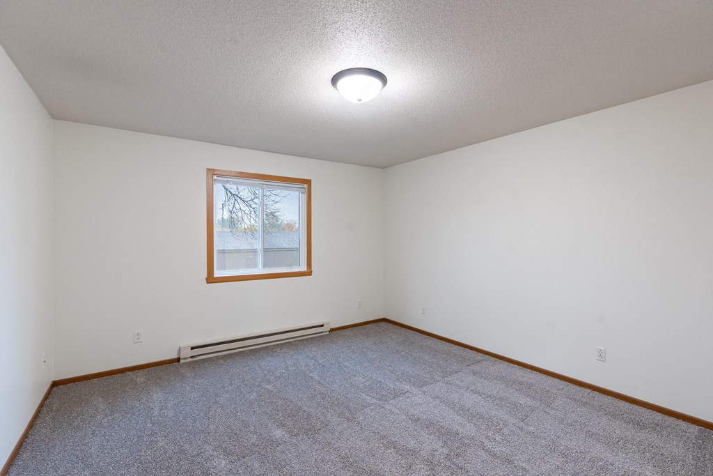 a bedroom with carpet and a window. Fargo, ND Brownstone Apartments