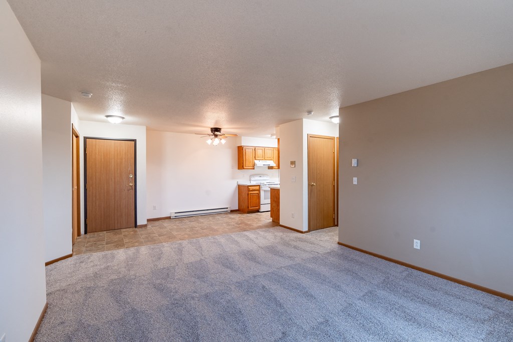 an empty living room with a kitchen in the background. Fargo, ND Brownstone Apartments
