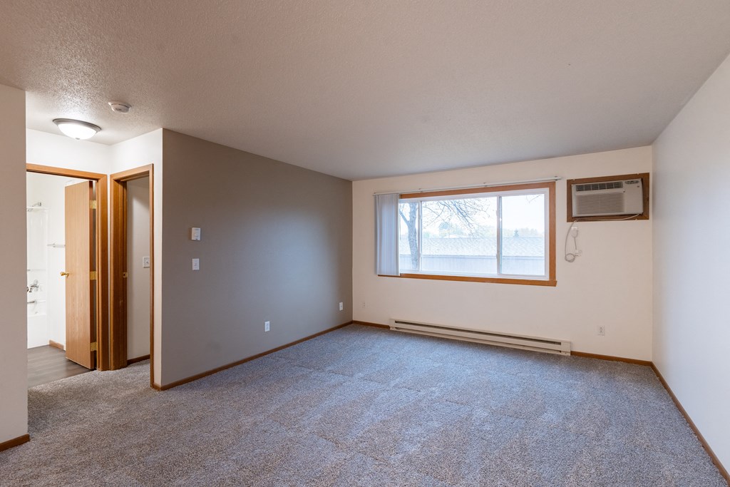 the living room of an empty house with a large window. Fargo, ND Brownstone Apartments