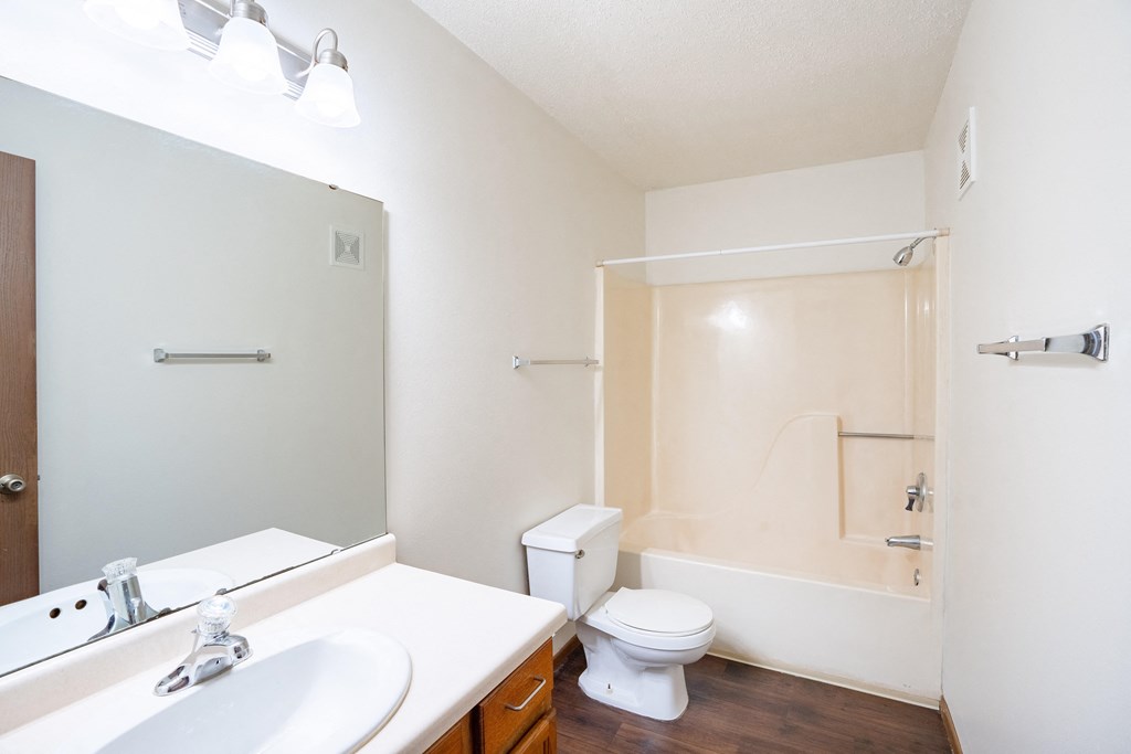 a bathroom with a toilet and a sink and a mirror. Fargo, ND Carlton Place Apartments