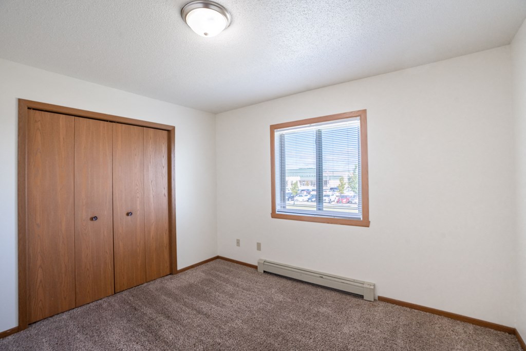a bedroom with a window and a closet. Fargo, ND Carlton Place Apartments