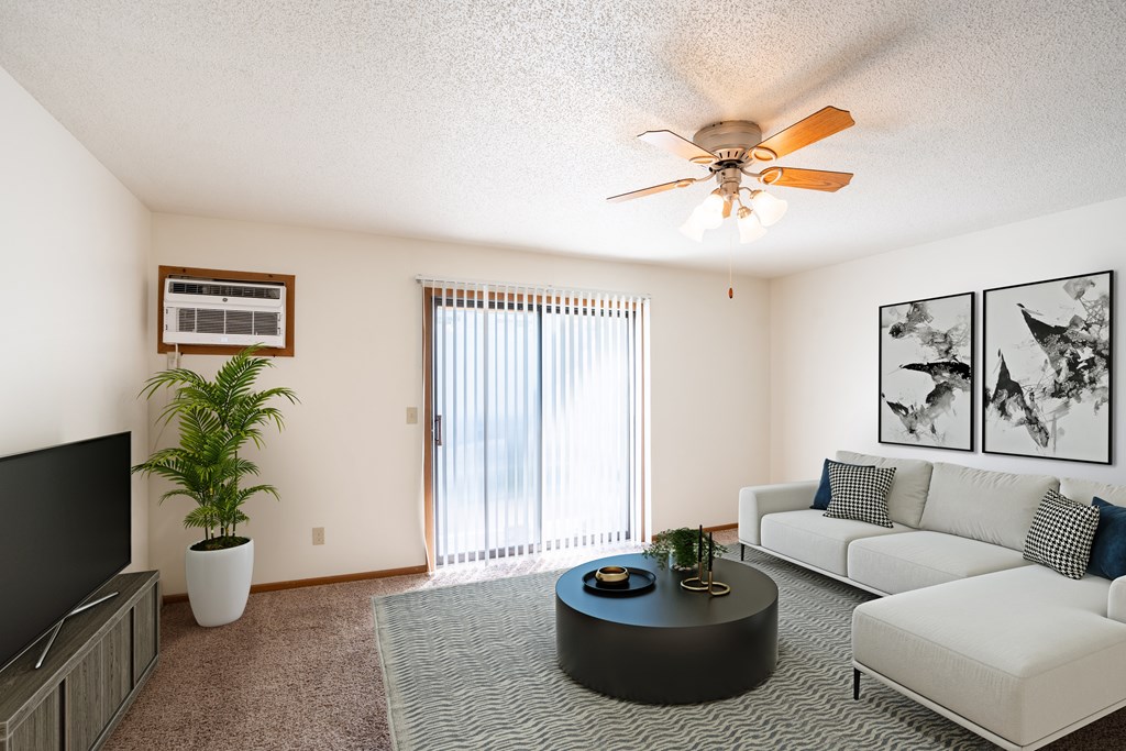 a living room with a couch and a coffee table and a ceiling fan. Fargo, ND Carlton Place Apartments