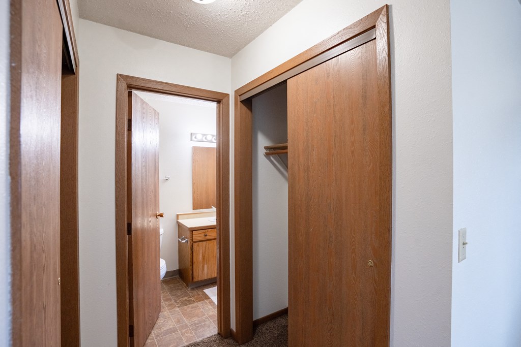 a bathroom with two doors and a closet with a sink and a mirror. Fargo, ND Cedar Pointe Apartments