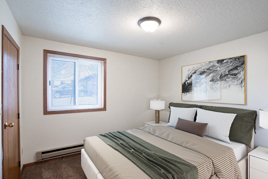 a bedroom with a bed and a window. Fargo, ND Cedar Pointe Apartments
