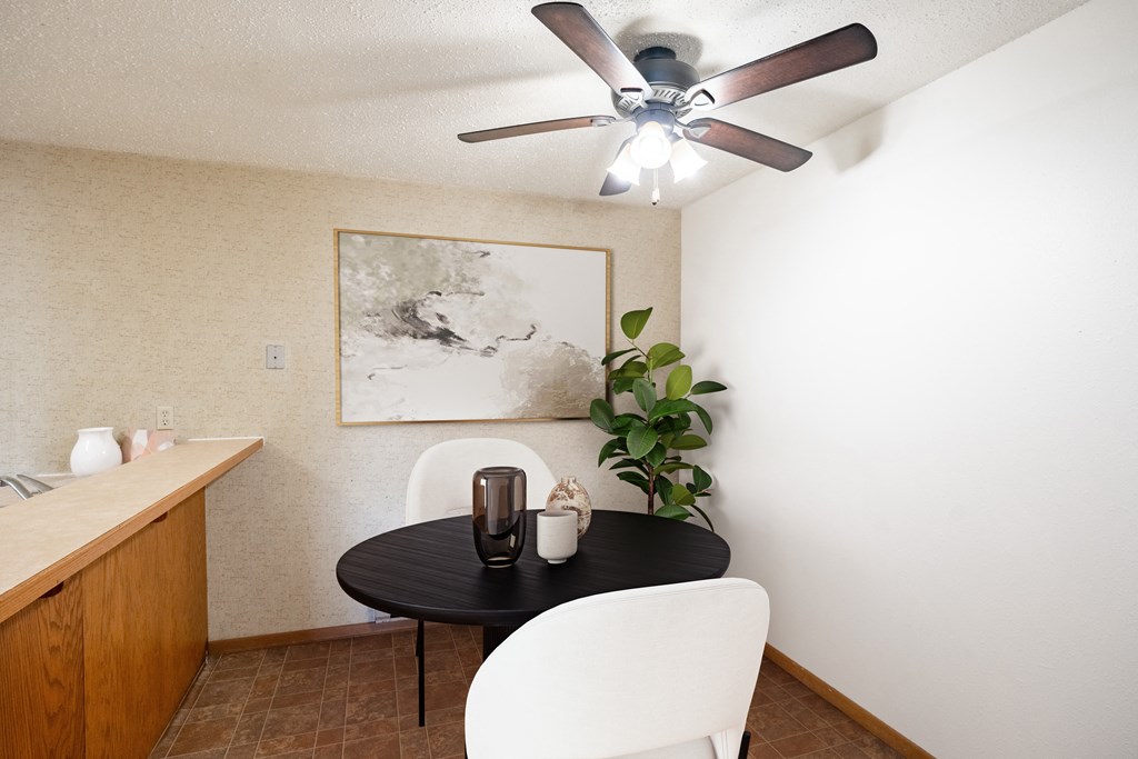 a dining room with a table and chairs and a ceiling fan . Fargo, ND Cedar Pointe Apartments