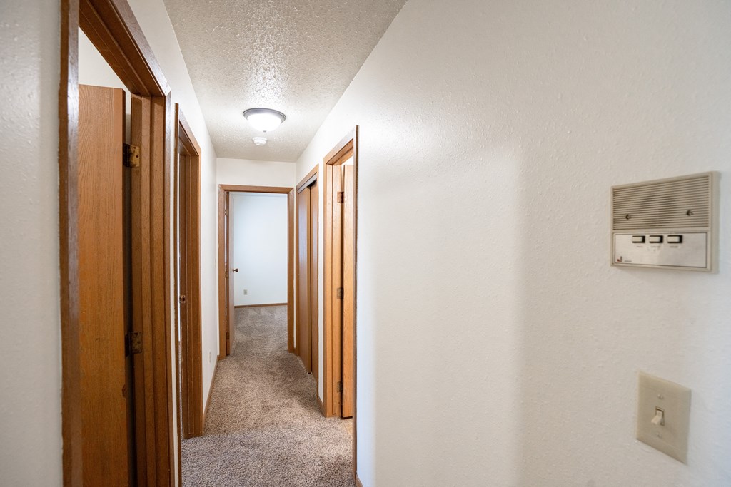a hallway with wood doors and a light on the ceiling. Fargo, ND Cedar Pointe Apartments