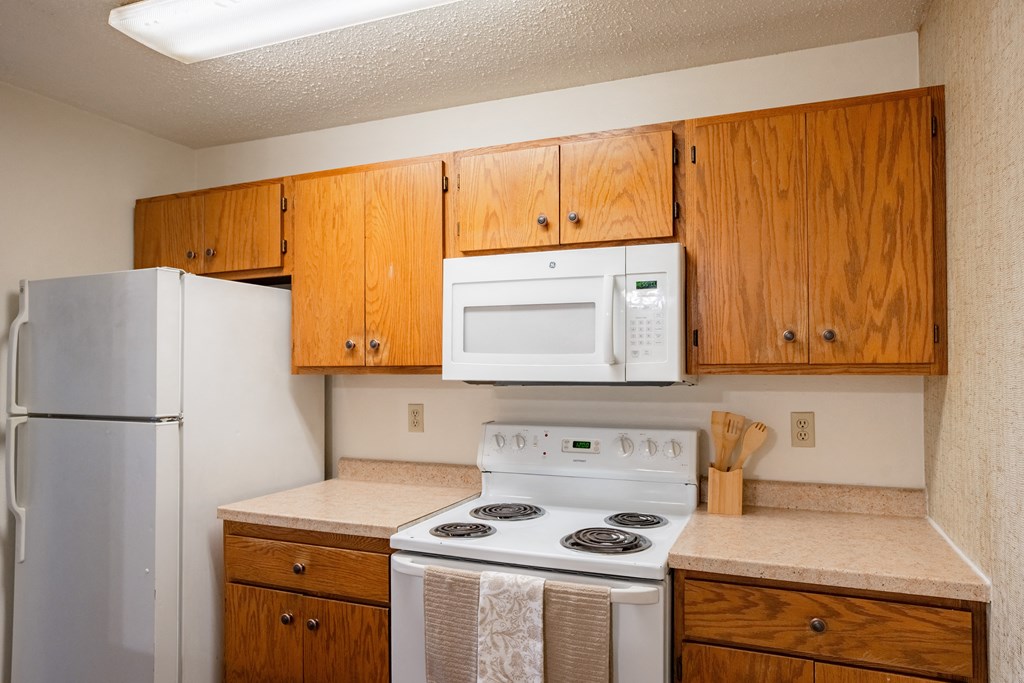 a kitchen with white appliances and wooden cabinets and a refrigerator. Fargo, ND Cedar Pointe Apartments