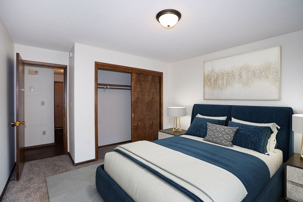 a bedroom with a bed and a closet and a door to a bathroom.  Fargo, ND Country Club Apartments
