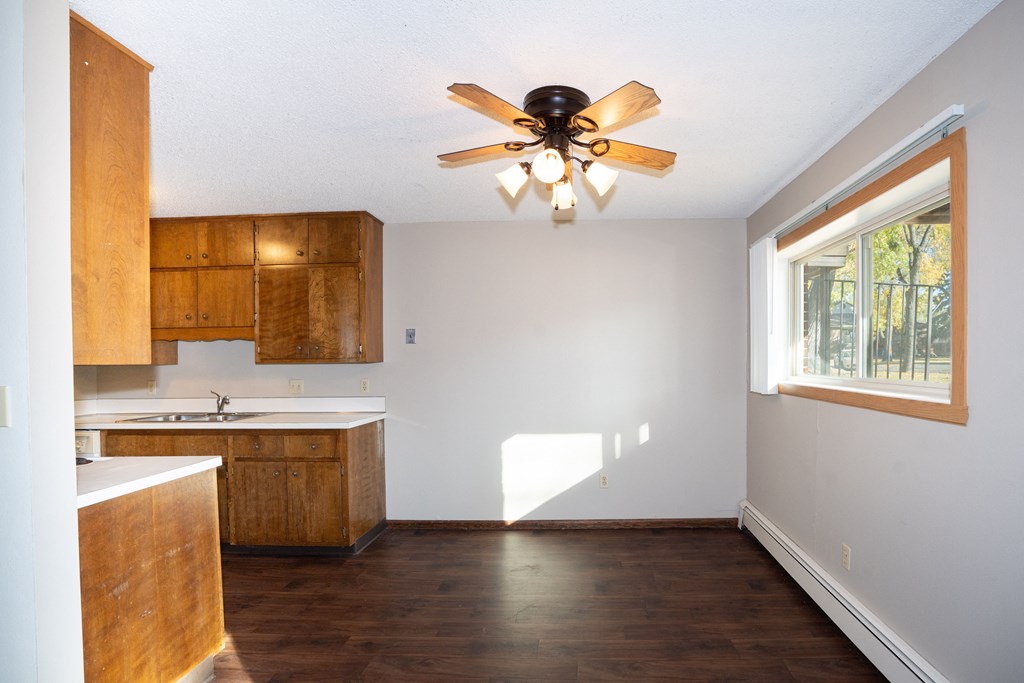 an empty kitchen with a ceiling fan and a window. Fargo, ND Country Club Apartment