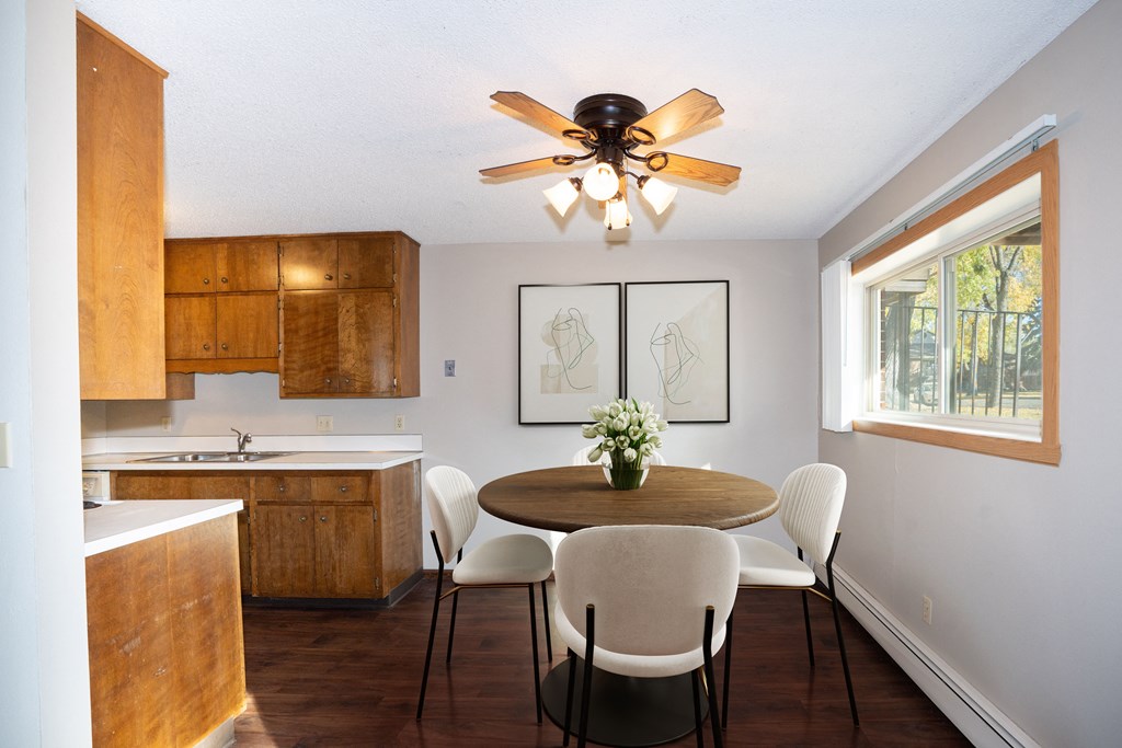 a kitchen with a table and chairs and a ceiling fan. Fargo, ND Country Club Apartments