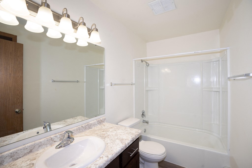 a bathroom with a sink and a shower and a toilet. Fargo, ND Country Club Apartments