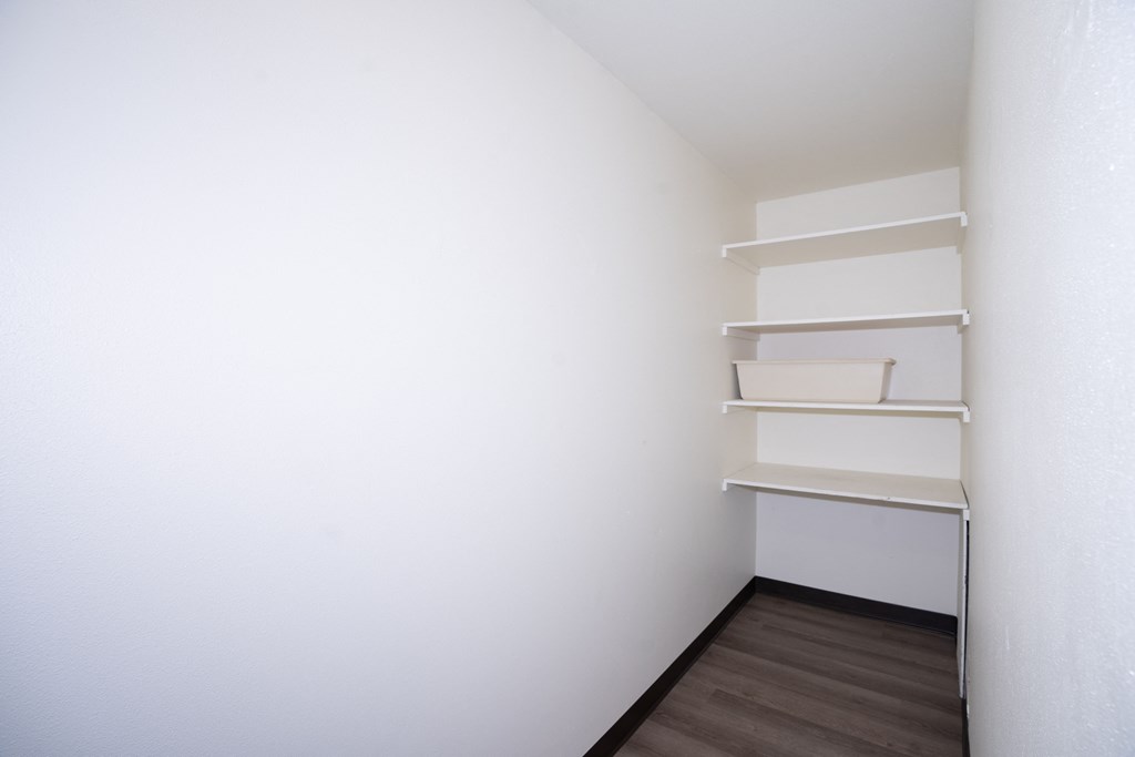 a room with white walls and shelves and a wooden floor. Fargo, ND Country Club Apartments