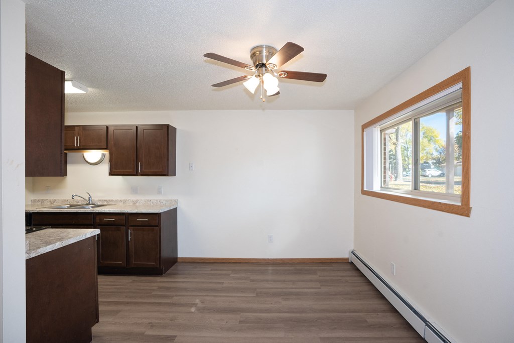 an empty kitchen with a ceiling fan and a window. Fargo, ND Country Club Apartments