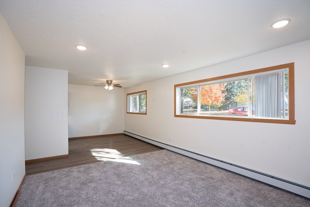 a living room with a large window and a carpet. Fargo, ND Country Club Apartments