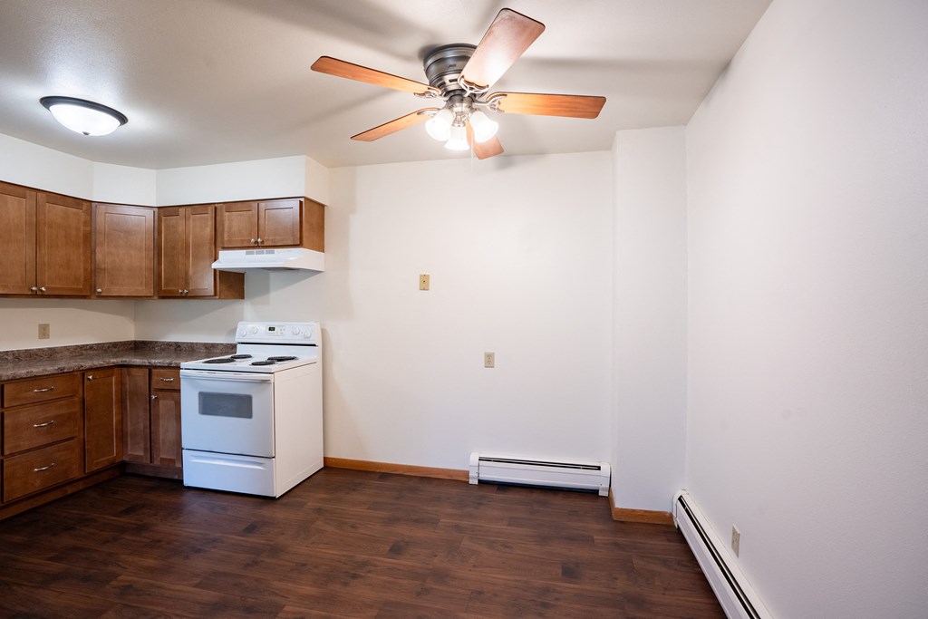 an empty kitchen with white appliances and a ceiling fan. Fargo, ND Crown Court 1 Apartments