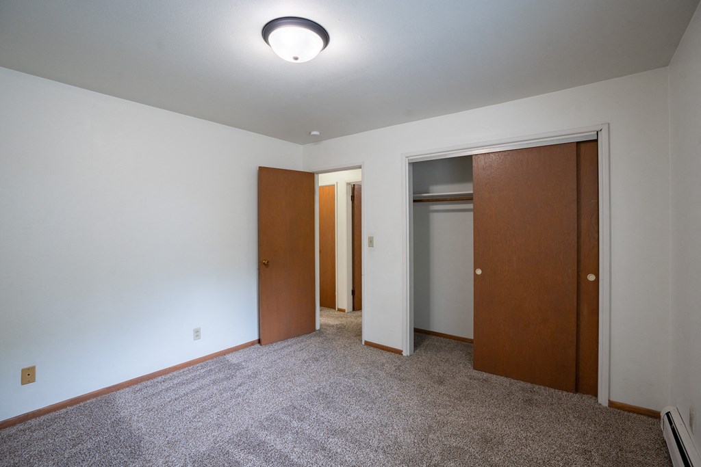 a bedroom with a closet and a door to a bathroom.  Fargo, ND Crown Court 1 Apartments