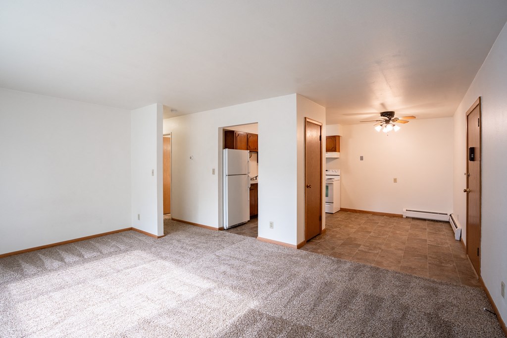 an empty living room with white walls and a ceiling fan. Fargo, ND Crown Court 1 Apartments