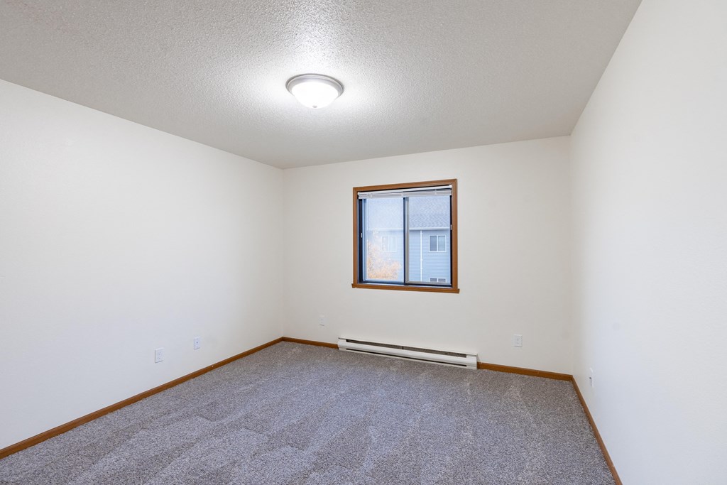a bedroom with carpet and a window. Fargo, ND Flagstone Apartments
