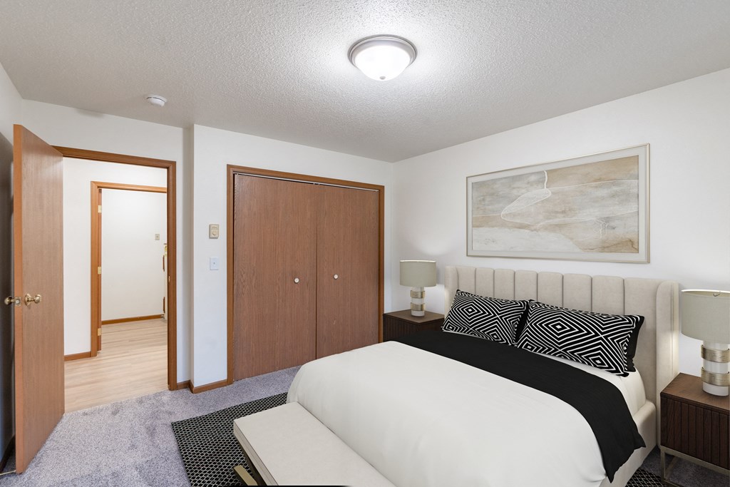 a bedroom with a bed and a closet and a door to a bathroom. Fargo, ND Flagstone Apartments