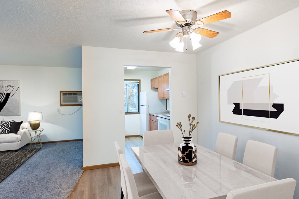 our living room and dining room with a white table and chairs and a ceiling fan. Fargo, ND Flagstone Apartments