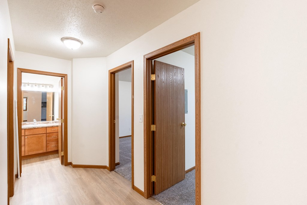 a living room with a door to a bathroom and a mirror. Fargo, ND Flagstone Apartments