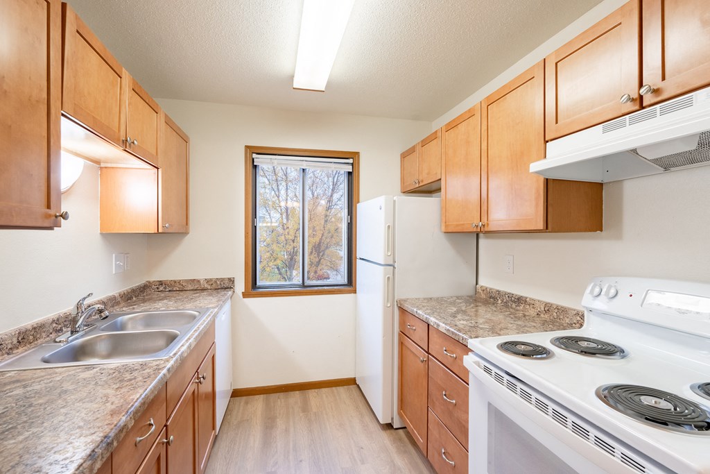 an empty kitchen with a stove refrigerator and sink. Fargo, ND Flagstone Apartments