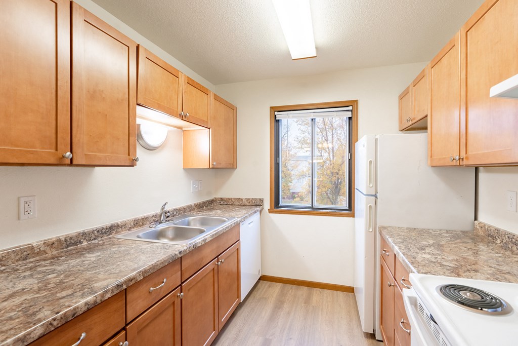 an empty kitchen with wooden cabinets and granite counter tops. Fargo, ND Flagstone Apartments