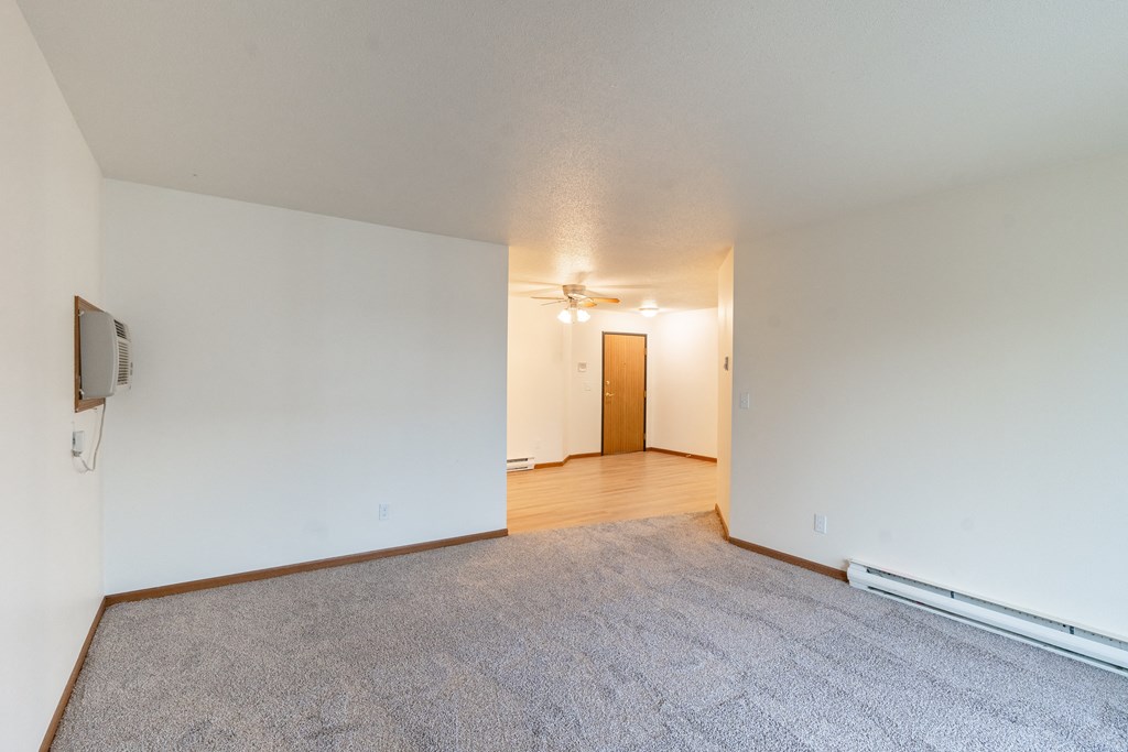 the living room and dining room of an apartment with white walls and wood flooring. Fargo, ND Flagstone Apartments