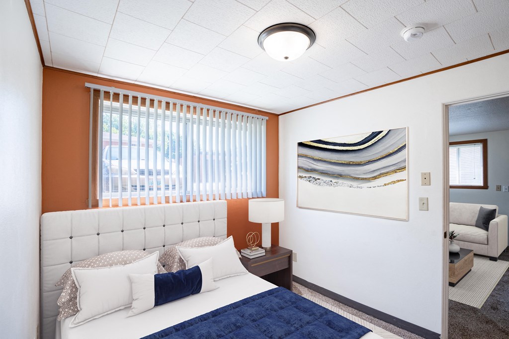 a bedroom with a bed and a painting on the wall. Fargo, ND Forest Avenue Apartments