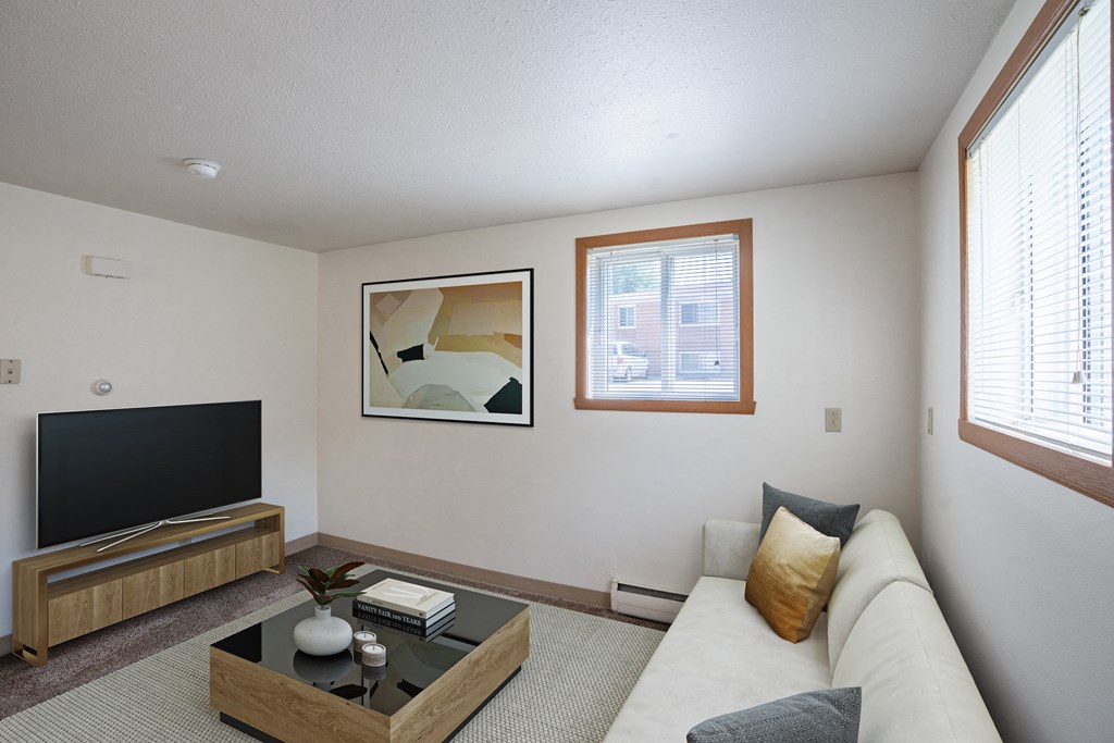 a living room with a couch and a coffee table and a television. Fargo, ND Forest Avenue Apartments