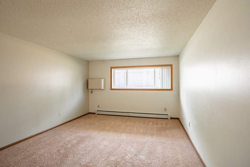 the living room of an empty house with a window. Fargo, ND Hawn Apartments