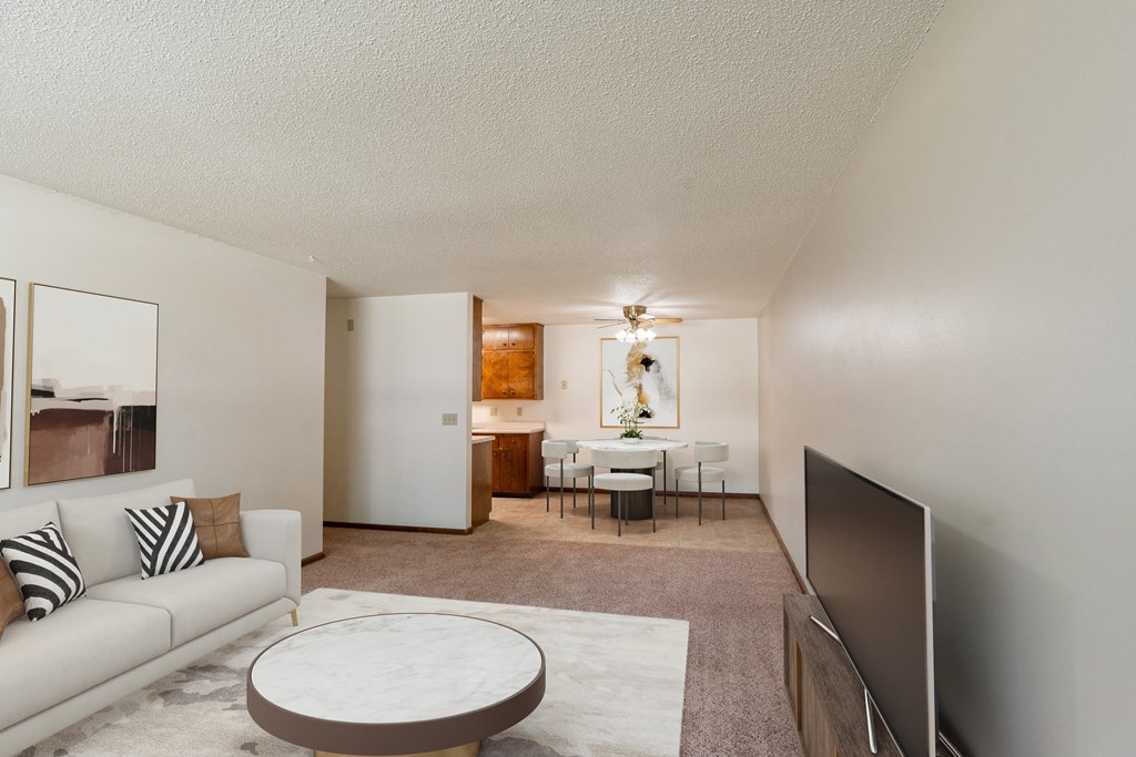 a living room with a couch and a coffee table and a dining room and kitchen. Fargo, ND Hawn Apartments